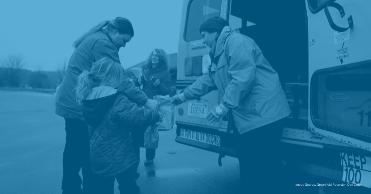 School nutrition employee handing out meals from the back of a school bus to a family school lunch hero day 2020 COVID-19